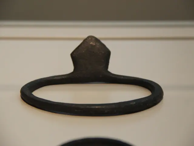 The image shows a close up of a black ring on a white surface, which appears to be a bottle opener....