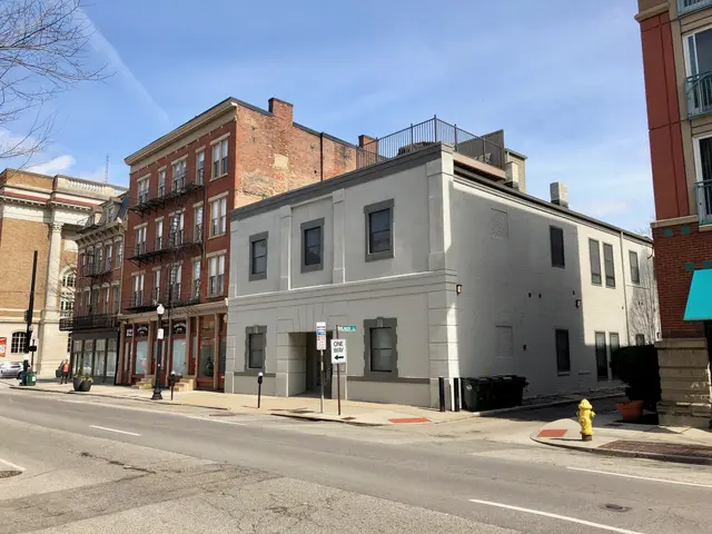 The image shows a city street with a fire hydrant on the side of it, surrounded by buildings with...