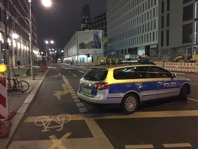 The image shows a police car parked on the side of a street at night, surrounded by buildings,...