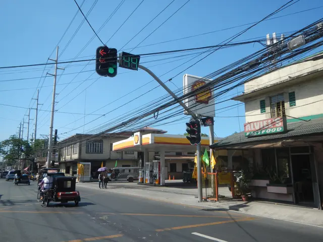 The image shows a street with a gas station in the background. There are vehicles on the road,...