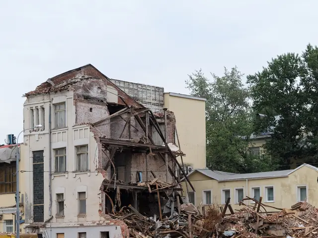 The image shows a building that has been partially demolished on the side of a river, with water at...