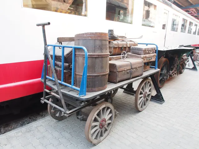 The image shows a train with a cart full of suitcases sitting on the side of it. The train is on...